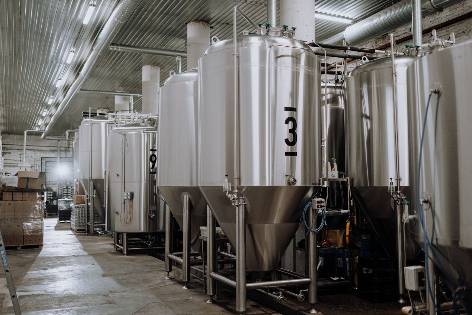 Stainless steel process tanks inside a clean industrial production room.